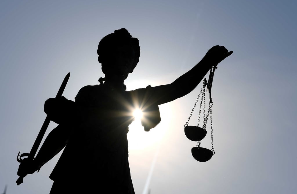 Eine Statue der Justitia steht mit Waage und Schwert in der Hand.