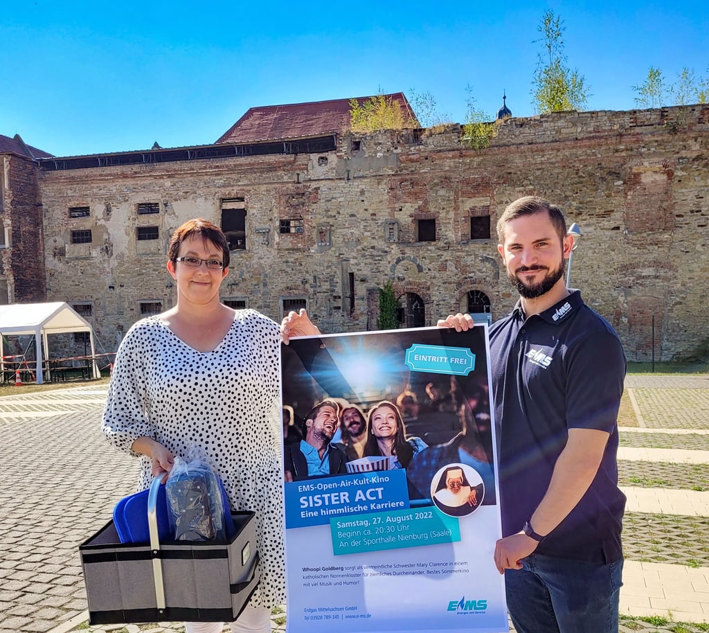 Bürgermeisterin Susann Falke und EMS-Marketingmanager Sebastian Rabach präsentieren das Plakat und den Präsentkorb am Veranstaltungsort.