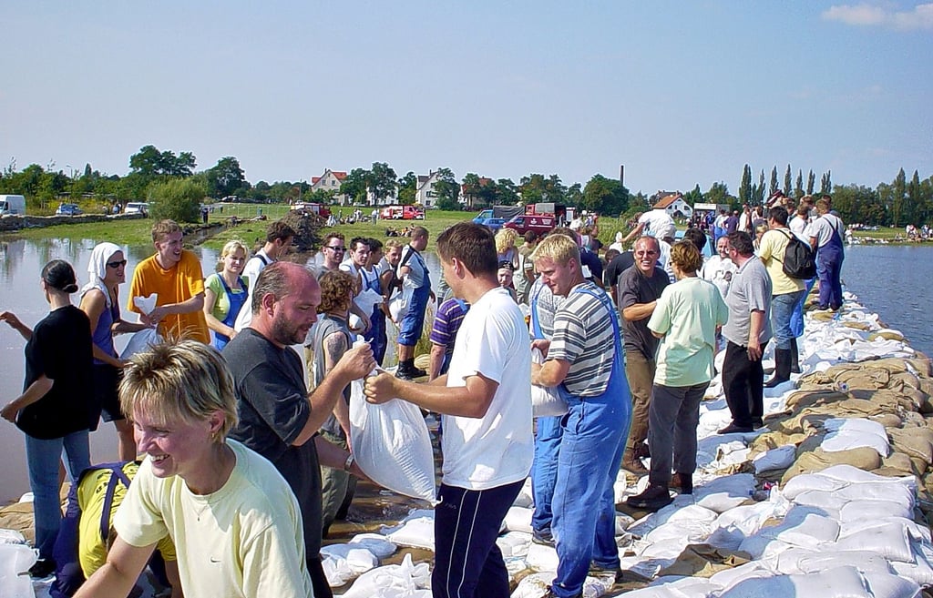 Unzählige Helfer bauen einen Sandsackdamm, um das Überlaufen der Goitzsche zu verhindern und Bitterfeld vor der Überflutung zu schützen.