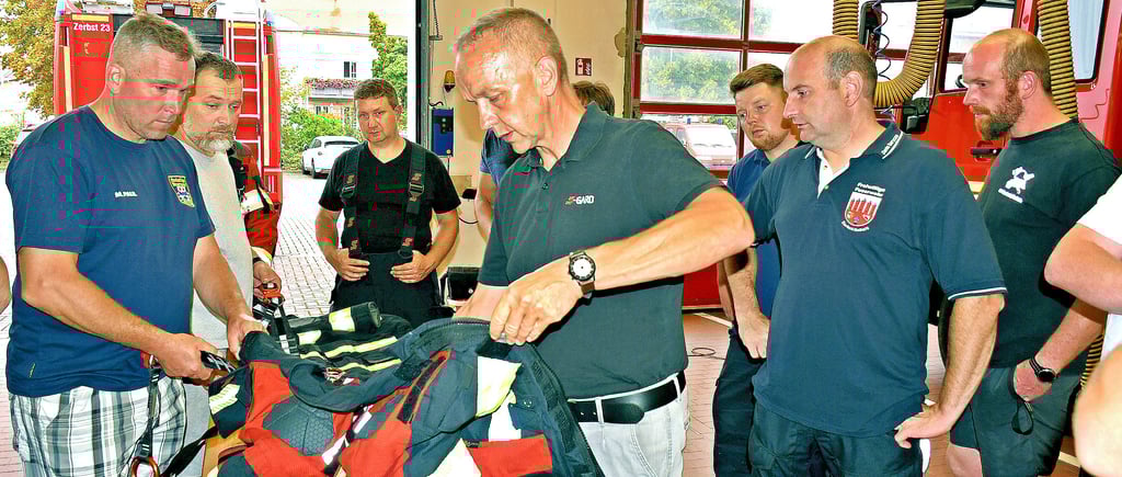 Die Zerbster Feuerwehren bekommen neue Einsatzkleidung. Michael Merboth (Mitte) von der Firma S-Gard erläutert, was die Kleidung alles kann.