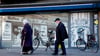 Eine Frau und ein Mann gehen an einem Wandbild im Stadtteil Kreuzberg vorbei.