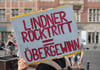 Ein Teilnehmer an der Demonstration "Lindner raus - Umverteilung jetzt!" steht mit einem Plakat vor der FDP-Bundesgeschäftsstelle.