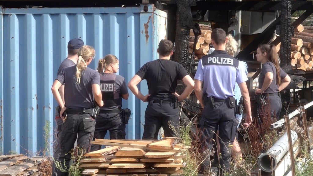 Ermittler der Polizei in Behnsdorf vor den Trümmern des Sägewerks.