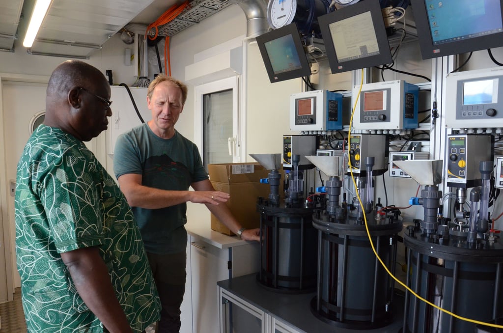 Dr. Nils Engler (rechts) von der Deutschen Biomasseforschungszentrum gGmbH (DBFZ) erläutert Prof. Komi Agboka von der Universität in Lomé in Togo die Funktion der Anlagentechnik.