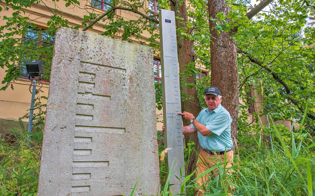 Klemens Koschig mit dem aktuellen Roßlauer Pegel und einem alten Pegelstein (links), der an der Rossel gefunden und wieder aufgestellt wurde.