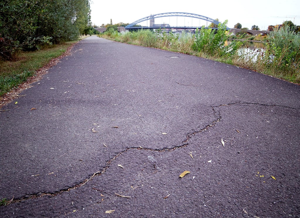 Markante Risse im Asphalt sollen in einer wassergebundenen Bauweise saniert werden.