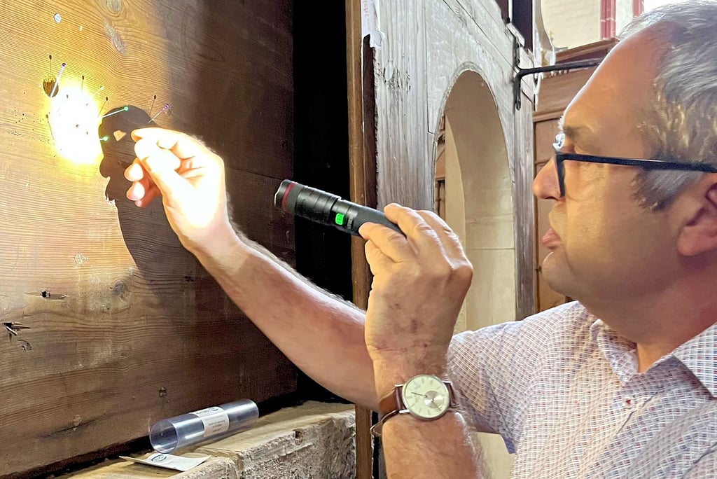 Torsten Heidecke untersucht die Fläche an der Rückseite des Altars in der Tangermünder St.-Stephanskirche. Hier wurden nach den ersten beiden Einsätzen der Schlupfwespen Stellen markiert, die eindeutig von den Wespen genutzt wurden. Deren Löcher im Holz sind wesentlich kleiner als die der Holzwürmer.