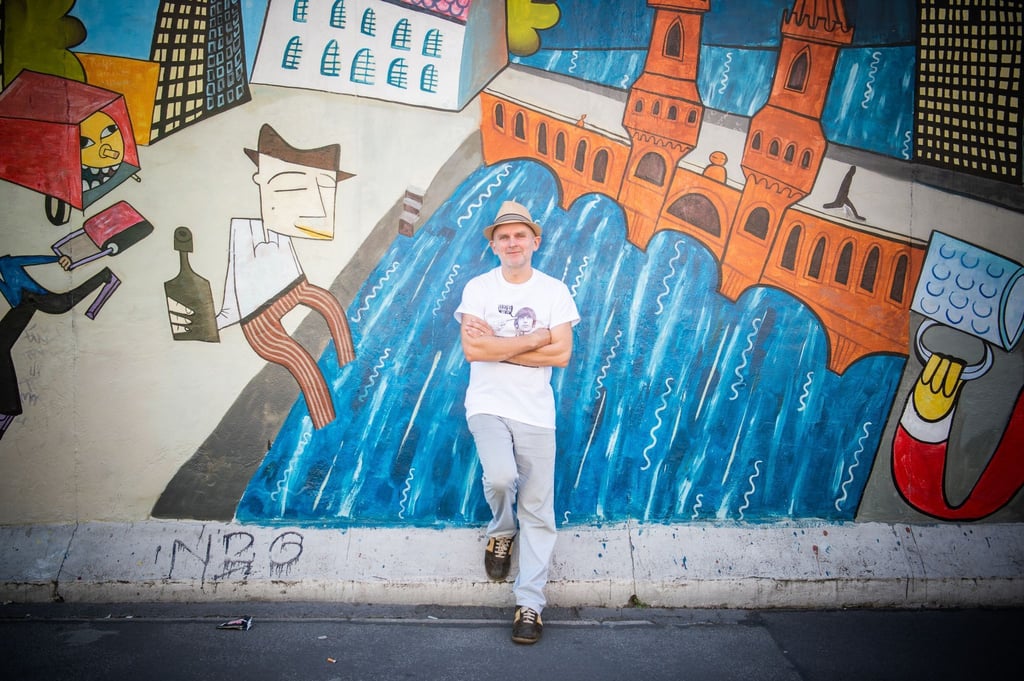 Jim Avignon steht vor seinem Werk an der East Side Gallery in Berlin.