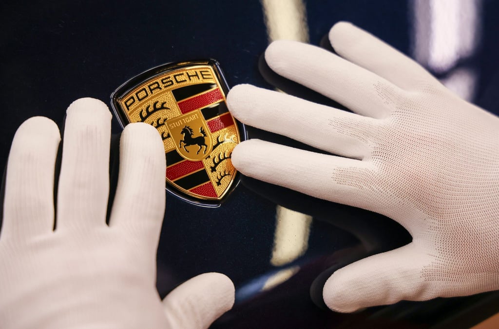 Ein Mitarbeiter befestigt das Wappen an einem Porsche Macan im Leipziger Porsche Werk.