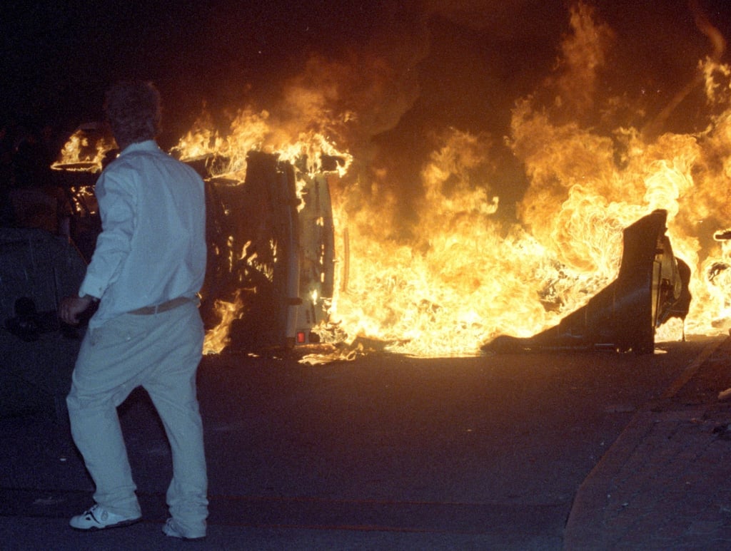 Brennendes Auto auf der Straße vor dem zentralen Asylbewerberheim von Mecklenburg-Vorpommern in Rostock-Lichtenhagen.