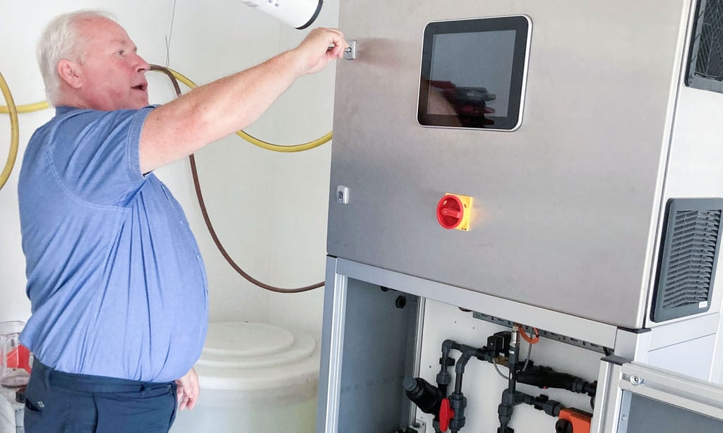 Detlef Töpfer gibt einen Einblick ins Innenleben der Hydrolyse-Maschine, die mit Sole aus dem dahinterstehenden Behälter mit Salztabletten gespeist wird.