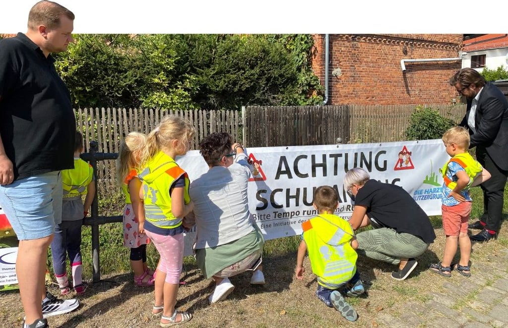 Zusammen mit Denny Behrendt (links) von der Harzer Blitzergruppe und Bürgermeister Maik Berger (rechts) hängen die Mühlenspatzen ein Banner in Anderbeck auf.