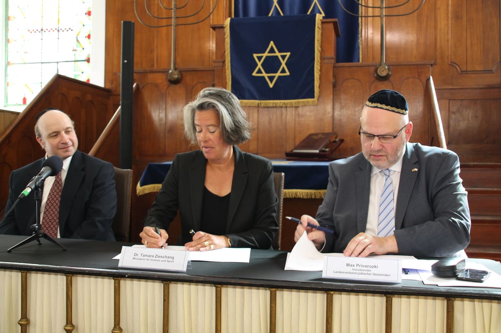 Der neue Polizeirabhbiner Daniel Fabian (rechts) neben Innenministerin Tamara Zieschang (CDU) und dem Landesvorsitzenden der jüdischen Gemeinden Max Privorozki bei der Unterzeichnung der Vereinbarung in der Synagoge in Halle.