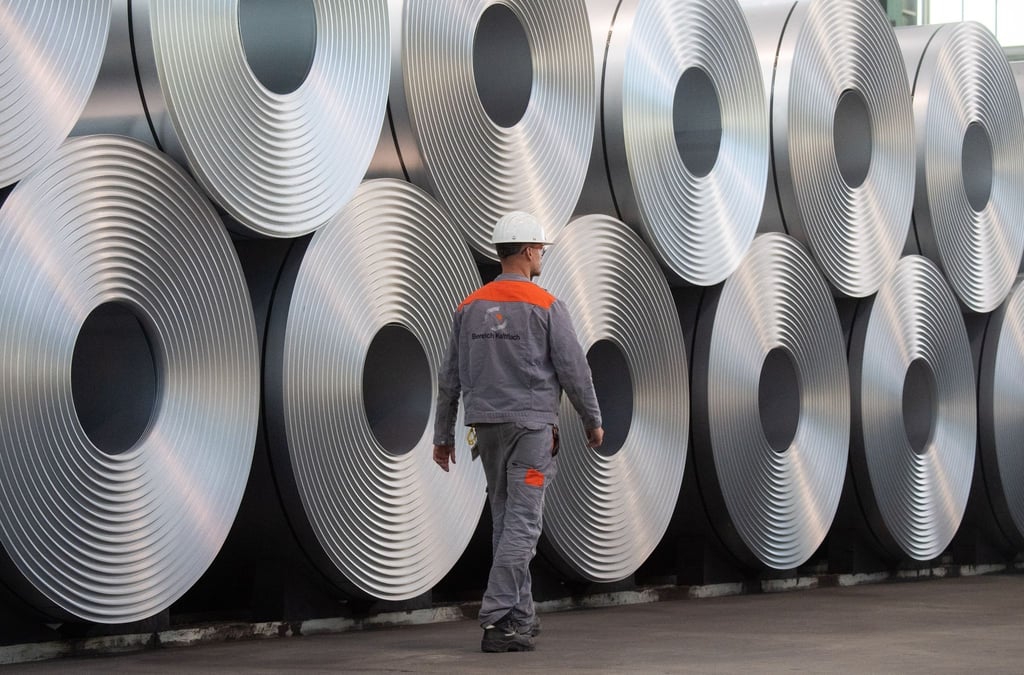 Ein Mitarbeiter geht bei der Salzgitter AG an aufgewickeltem Stahl vorbei.