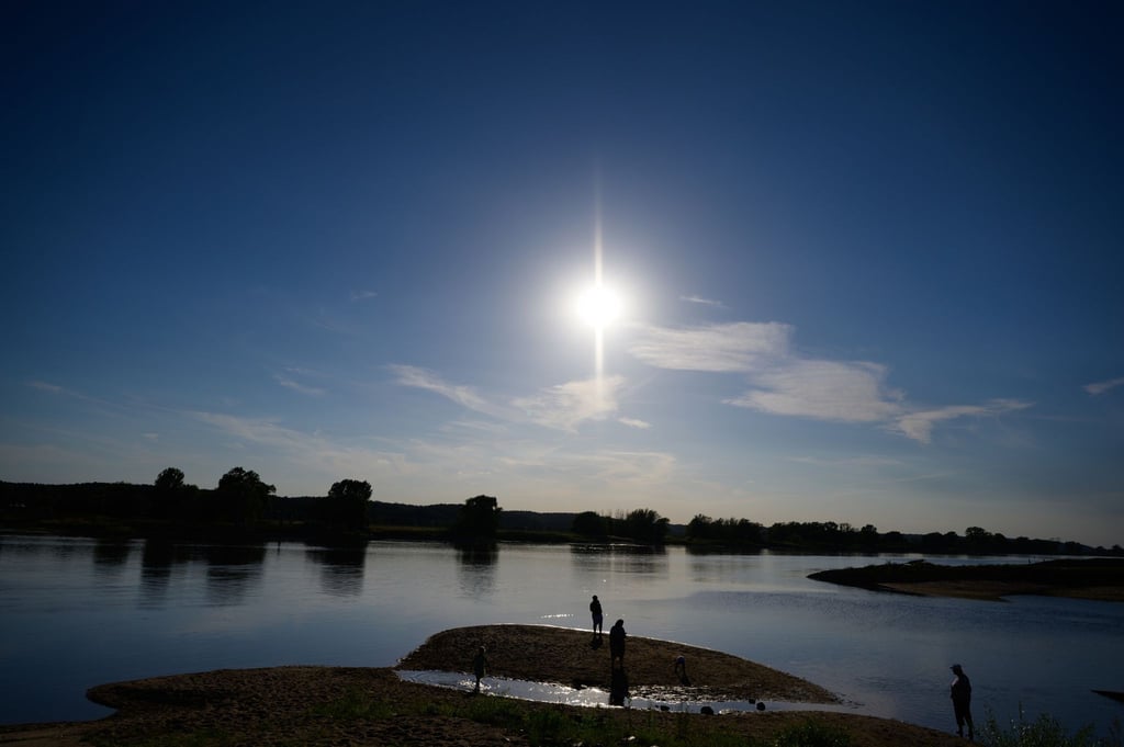 Menschen stehen bei Niedrigwasser am Ufer eines Flusses.