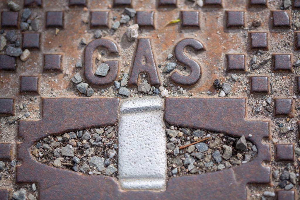 Der Schriftzug „Gas“ steht auf einer Straßenkappe.