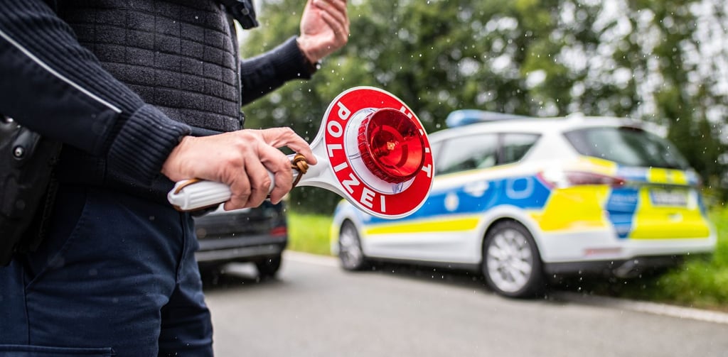 Eine Polizistin hält eine Winkerkelle in der Hand.