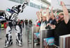Computerspiel-Fans feiern gemeinsam mit einem Roboter den Einlass zur Messe.
