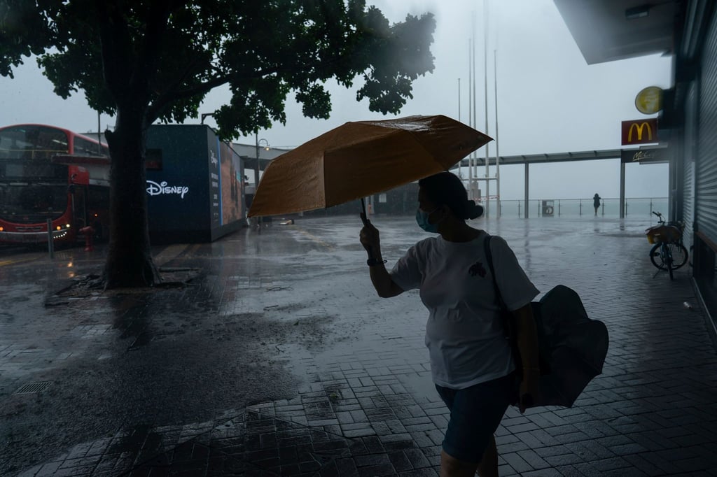 Eine Frau hält einen Regenschirm bei starkem Wind in der Nähe der Promenade von Victoria Habour, als der Tropensturm „Ma-on“ an Hongkong vorbeizieht.