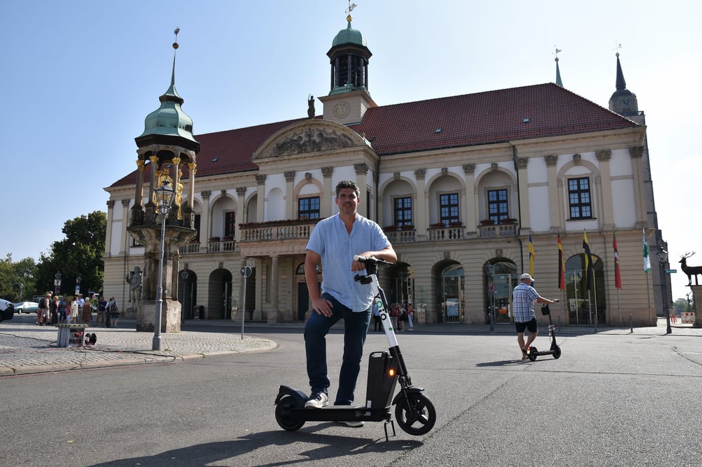 Boris M. Hillmann mit einem „Yoio“-Scooter vor dem Rathaus in Magdeburg. 150 dieser Elektrofahrzeuge sind in der Stadt unterwegs.