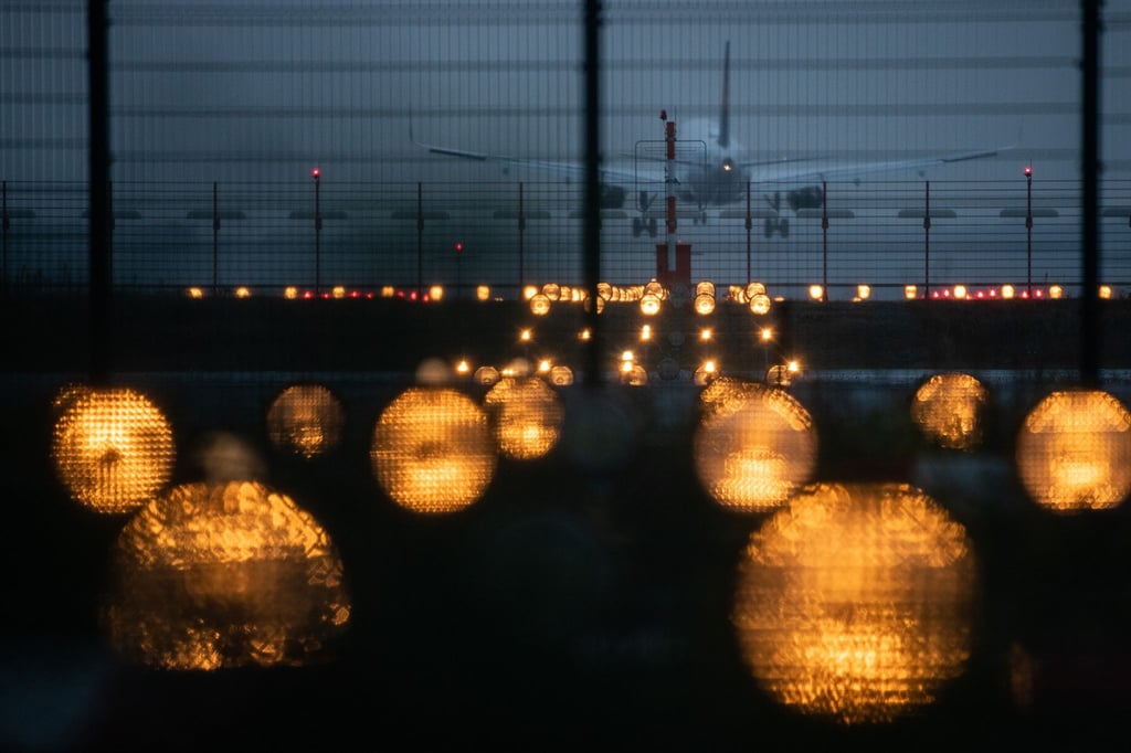 Ein Flugzeug landet hinter Signallichtern auf einem Flughafen.