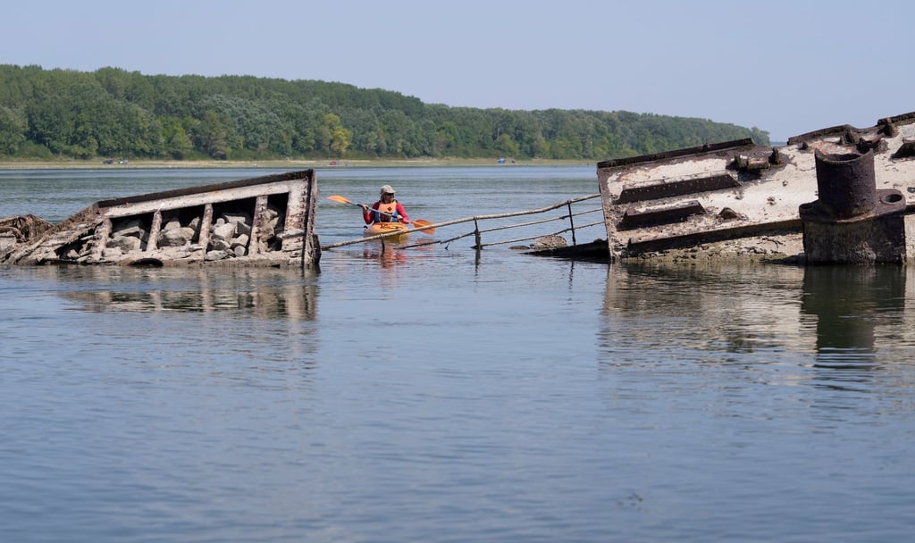 Ein Kajakfahrer paddelt bei niedrigem Wasserstand auf der Donau an einem Wrack eines aus dem Zweiten Weltkrieg stammenden Kriegsschiffs der Schwarzmeerflotte vorbei. Aufgrund der in Europa vorherrschenden Dürre sind mehrere Kriegsschiffe in der Donau freigelegt, die noch immer mit explosiver Munition beladen sind.