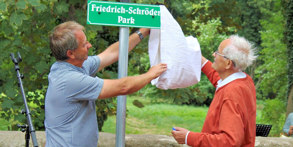 Bebertals Ortsbürgermeister Torsten Schmidt (l.) und Gerd-Friedrich Kaldrack, Nachfahre von Friedrich Schröder, enthüllen gemeinsam das Namensschild am Amtsgarten. Er trägt nun den Namen Friedrich-Schröder-Park.