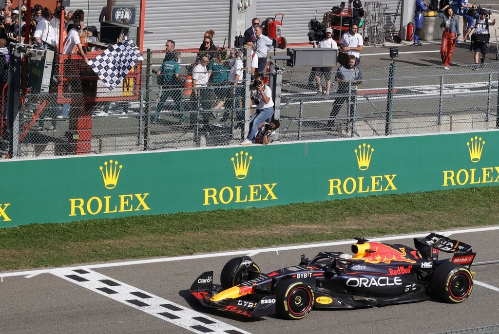 Ein Offizieller schwenkt die Zielflagge, während der Niederländer Max Verstappen als Sieger die Ziellinie überquert.