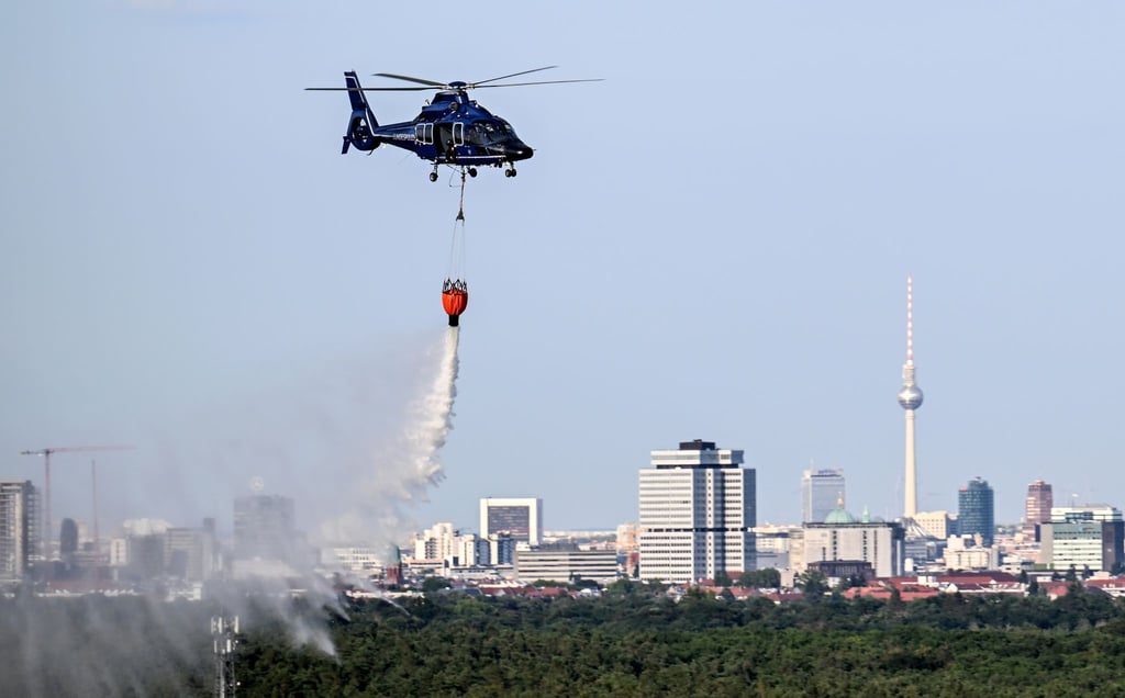 Ein Hubschrauber der Bundespolizei wirft Wasser über der Brandstelle im Grunewald ab.