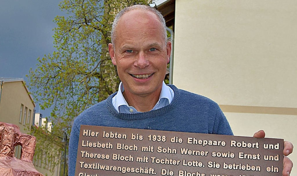 Eckart Reihlen zeigt die Bronzetafel, die zum Gedenken an das Schicksal der jüdischen Familie Bloch, an der Natursteinmauer befestigt wird.