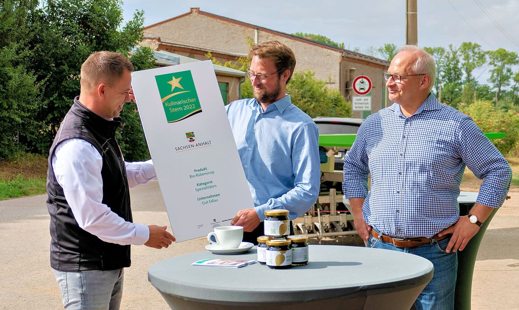 Dr. Jörg Bühnemann (v. li.), Geschäftsführer der Agrarmarketinggesellschaft Sachsen-Anhalt, übergibt das Hofschild zum Gewinn des Kulinarischen Sterns 2022 an Leonard van Uelft, Betriebsleiter vom Gut Edlau. Gutsinhaber Dr. Christian Schmidt.