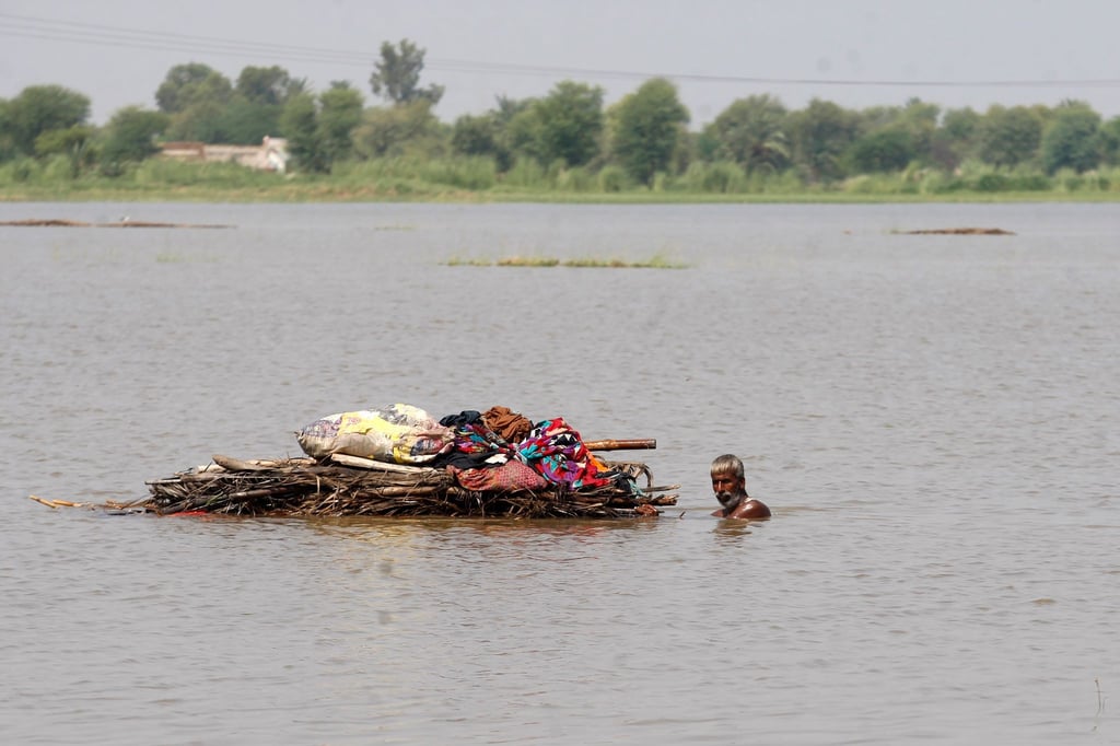 Ein Mann transportiert brauchbare Habseligkeiten aus seinem von der Flut zerstörten Haus in Pakistan.