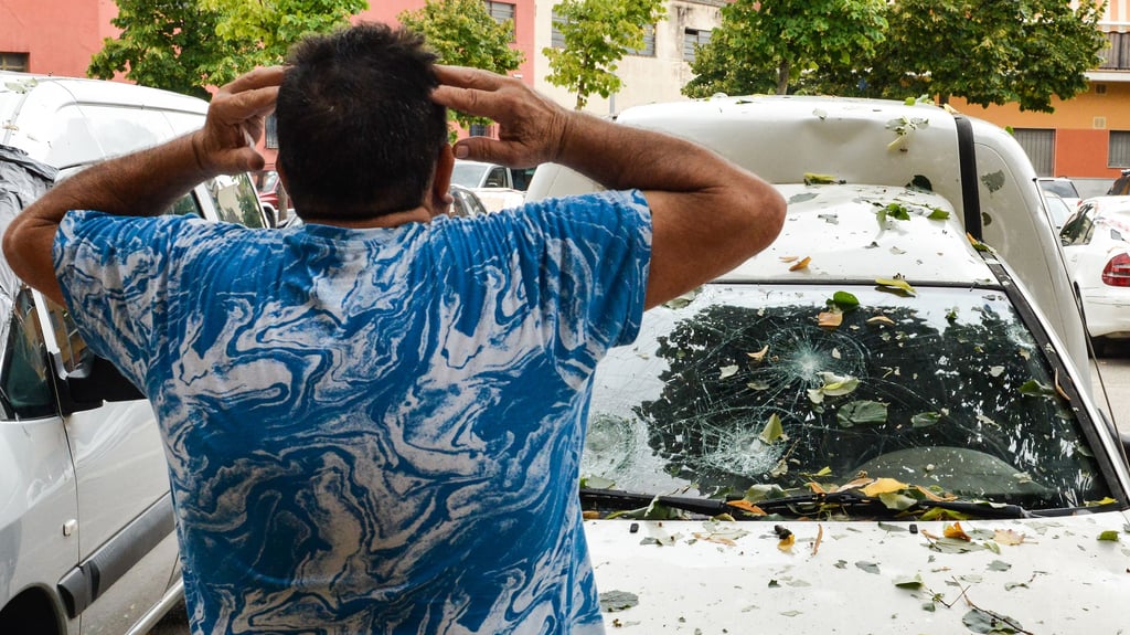 Ein Mann in La Bisbal D'empordà betrachtet die Schäden, die durch schwere Hagelschauer an seinem Auto entstanden sind.