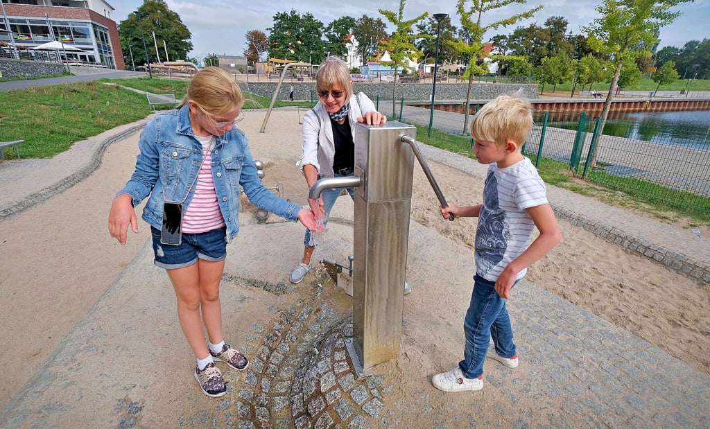 Regina Jarmuzek aus Dessau probiert mit ihren Enkeln den Wasserspielplatz am Stadthafen in Bitterfeld aus.