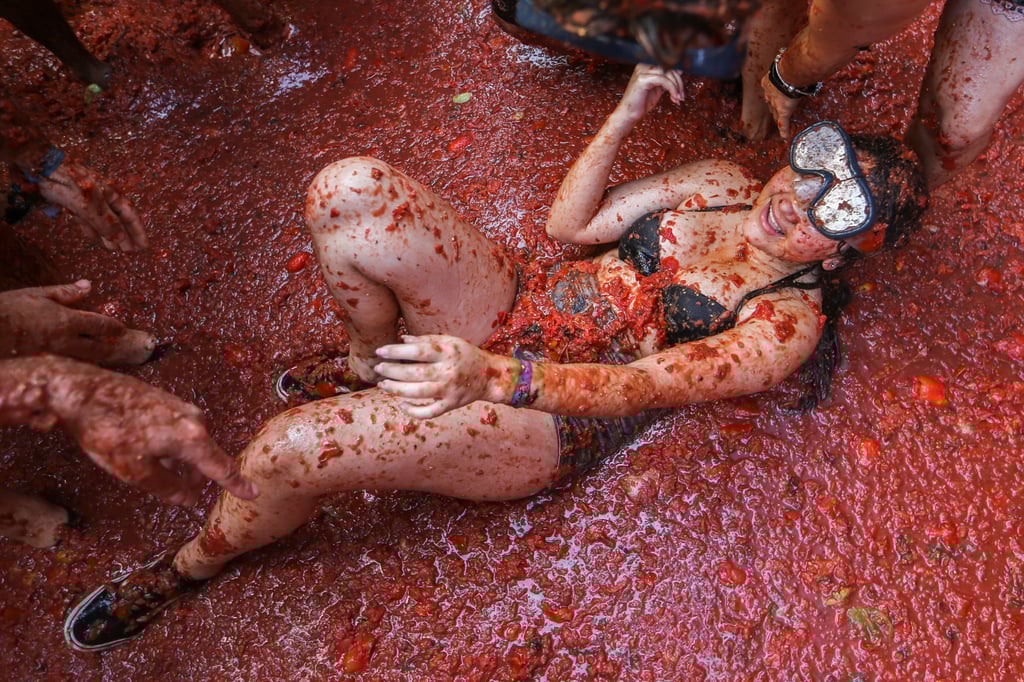 Eine Feiernde liegt in einer Pfütze aus zerquetschten Tomaten während der jährlichen traditionsreichen Tomatenschlacht «La Tomatina».