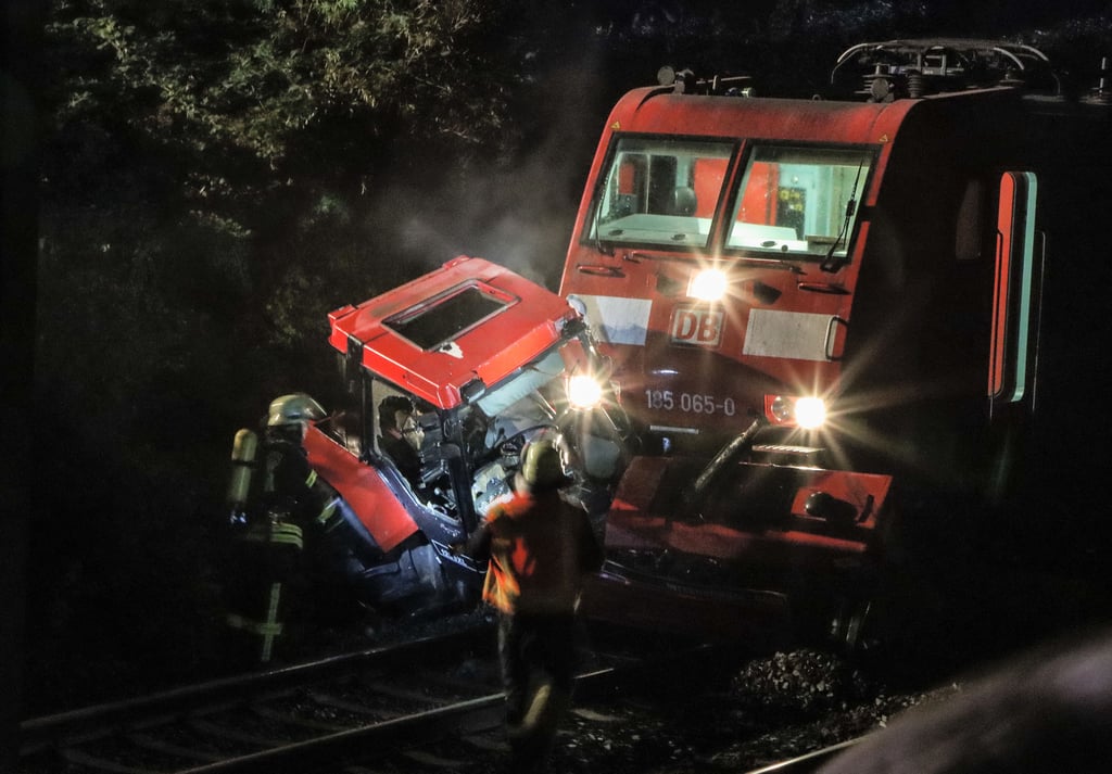 Ein Traktor klemmt halb unter einer Lok eines Güterzugs bei Kirchhain: Feuerwehrleute arbeiten an der Unfallstelle.