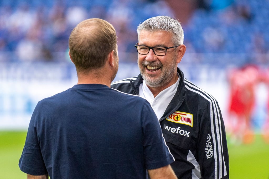 Ein Kollege begrüßt Union Berlins Trainer Urs Fischer (r) im Stadion.