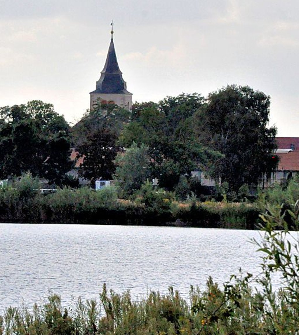 Blick über den Adamsee in Barleben auf den Turm der evangelischen Kirche in der Gemeinde.
