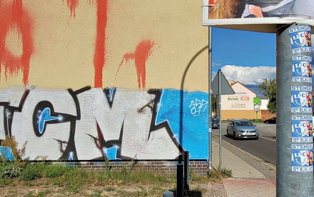 Das Bild in der Nähe der Stendaler Schützenplatz-Kreuzung fasst alles zusammen: An der Hauswand prangen eine FCM-Graffiti und eine linksextreme Schmiererei. Der Pfahl des Verkerkehrsschildes ist mit Aufklebern des Magdeburger Fußballvereins übersäht.