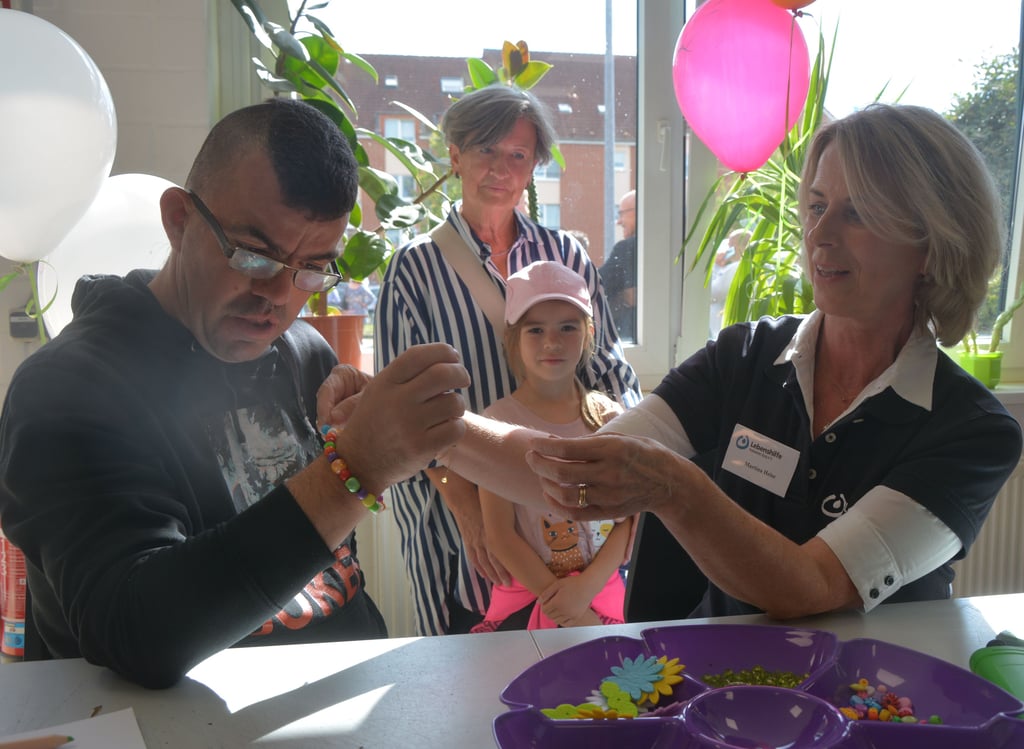 Lebenshilfe-Mitarbeiterin Martina Heise (r.) hilft beim Basteln vom Armreifen.