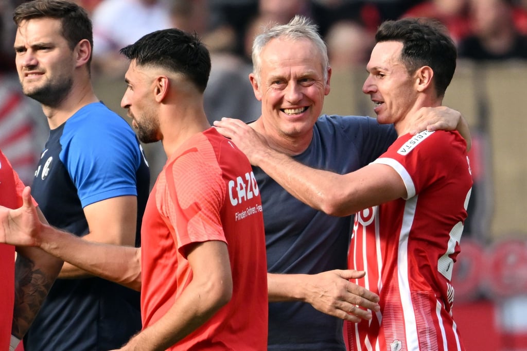Freiburgs Trainer Christian Streich (l) freut sich mit seinen Spielern nach dem Sieg in Leverkusen.