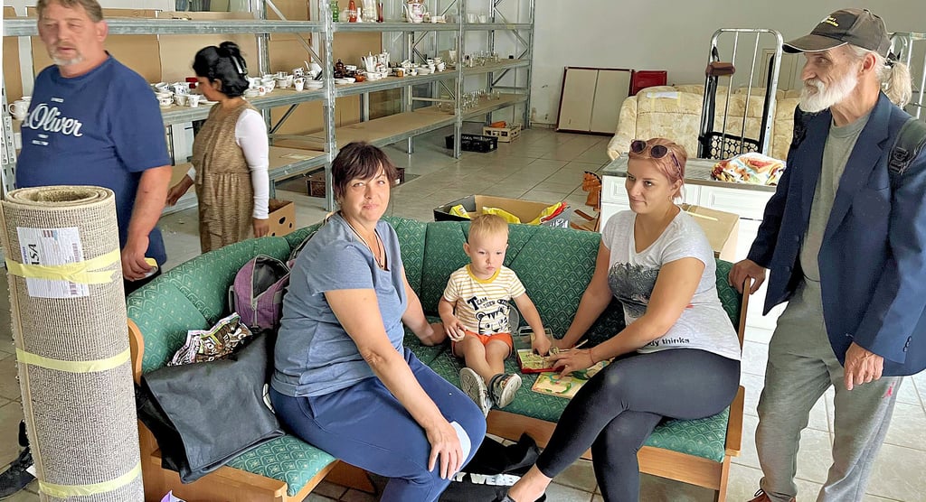 Die Regale im Spendenlager in Tangerhütte sind fast leer. Ludmila (sitzend von links) und Timur mit Mama Inna unterhalten sich. So wie sie warten auch andere Flüchtlinge immer dienstags und donnerstags auf neue Spenden.