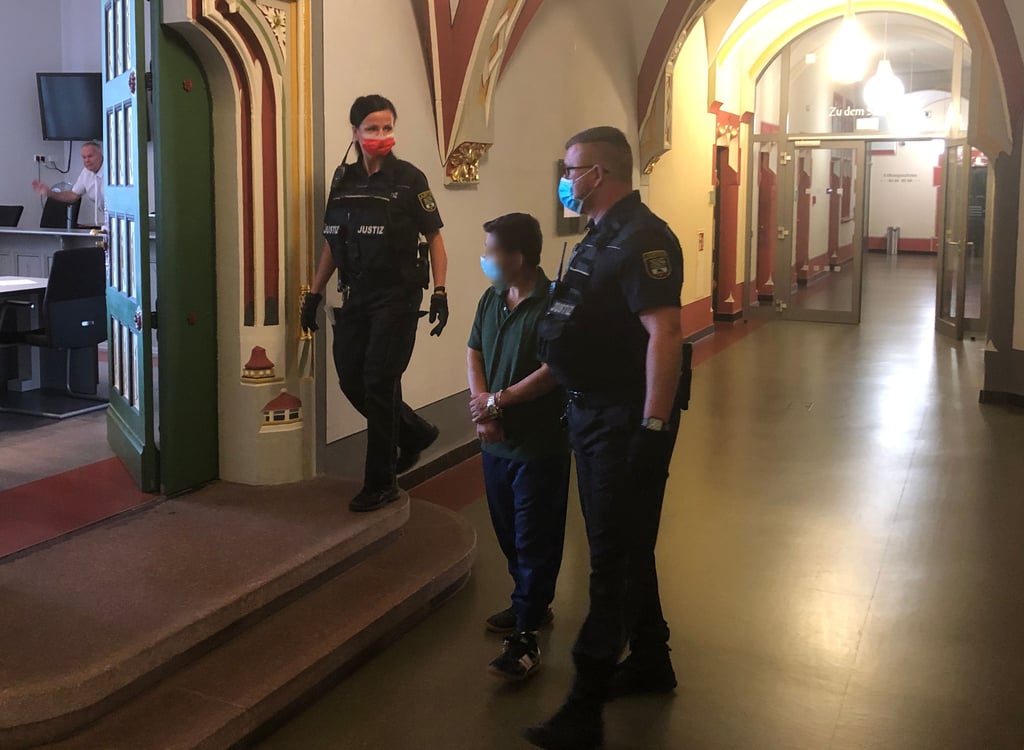 Justizbeamte führen den Angeklagten in den Gerichtssaal. Er soll eine 31-Jährige in Eilsleben auf offener Straße mit einem Messer angegriffen haben.