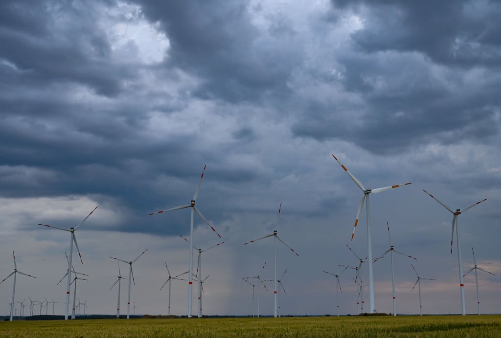 Dunkle Regenwolken ziehen über die Landschaft mit einem Windenergiepark.