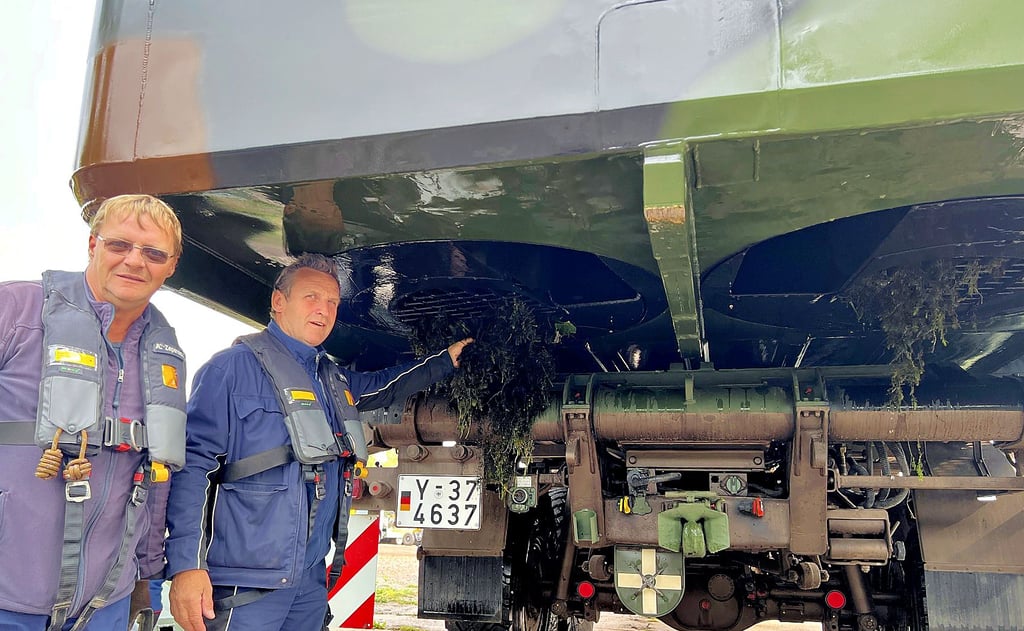 Die Bootsführer Andreas Zepernick und Uwe Voigt entfernen an der Unterseite des Motorbootes die vom Pump-Jet angesaugten Pflanzen. Etliche waren schon beim Transport abgefallen.