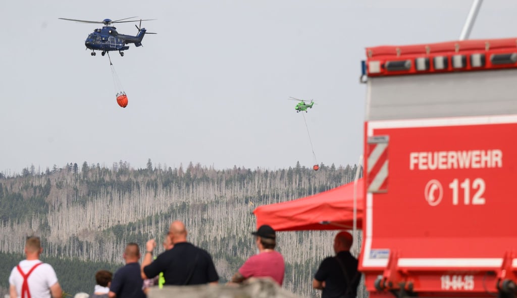 Hubschrauber mit Löschwasserbehältern bekämpfen einen Waldbrand am Brocken.