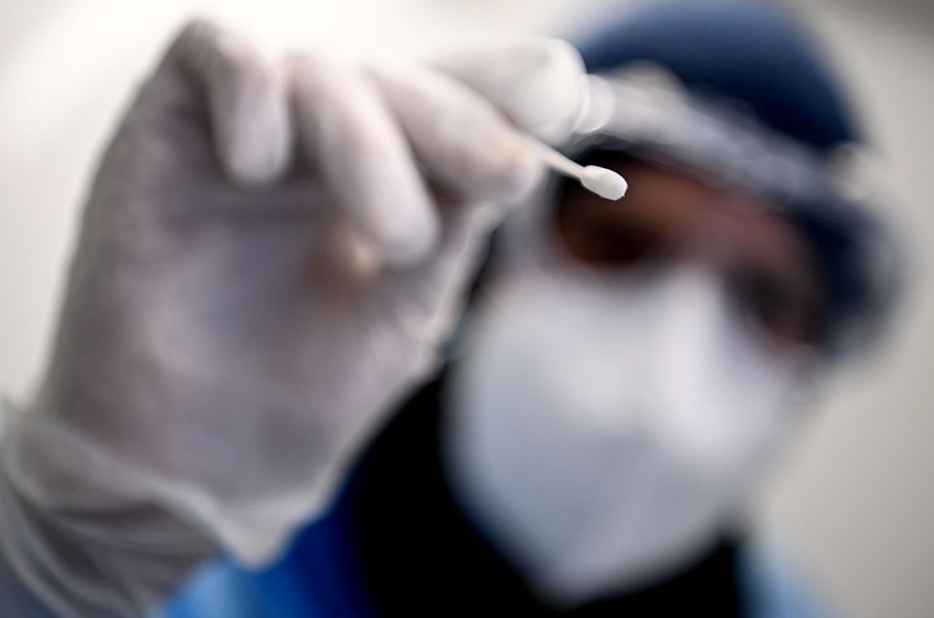 Ein Arzt hält ein Teststäbchen für die Entnahme einer Probe für einen Corona-Test in der Hand.