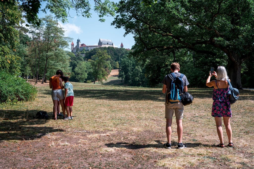 Touristen fotografieren die Veste Coburg vom Hofgarten aus. Der Tourismus in Bayern hat fast wieder Vor-Corona-Niveau erreicht.
