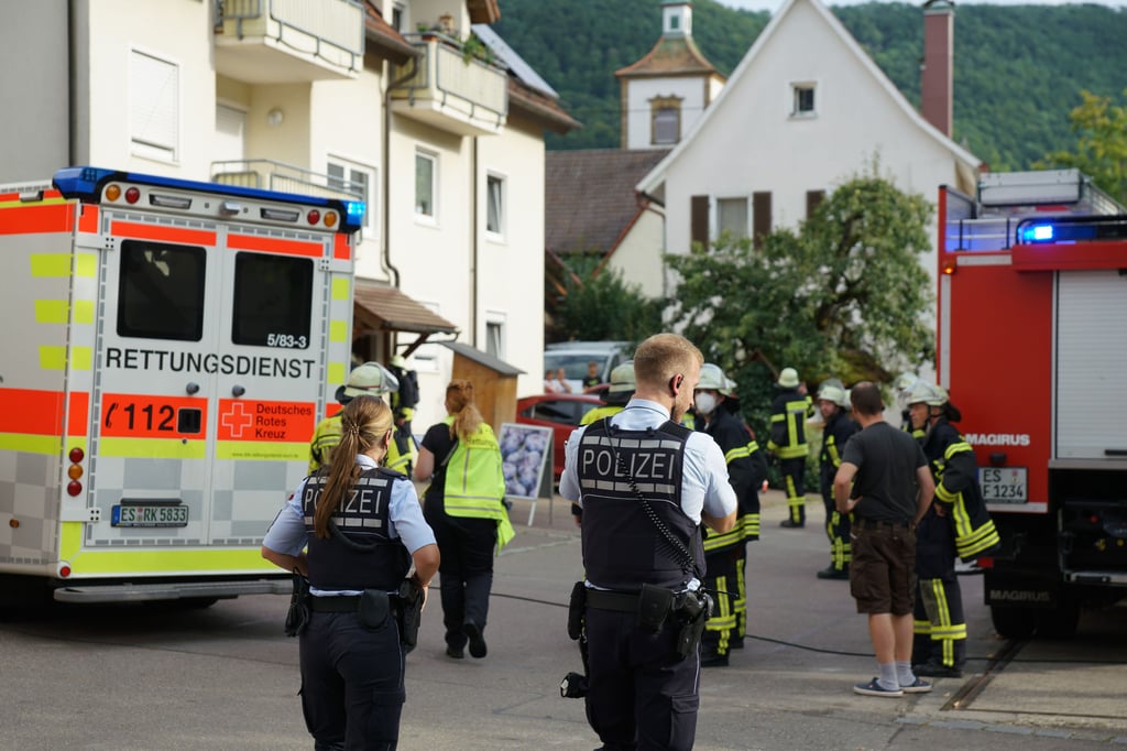 Polizei und Rettungskräfte stehen in einem Wohngebiet. In seiner Schnapsbrennerei ist ein 75 Jahre alter Mann ums Leben gekommen - seine Ehefrau wurde schwer verletzt. Die Polizei geht derzeit von einem Unfall aus.
