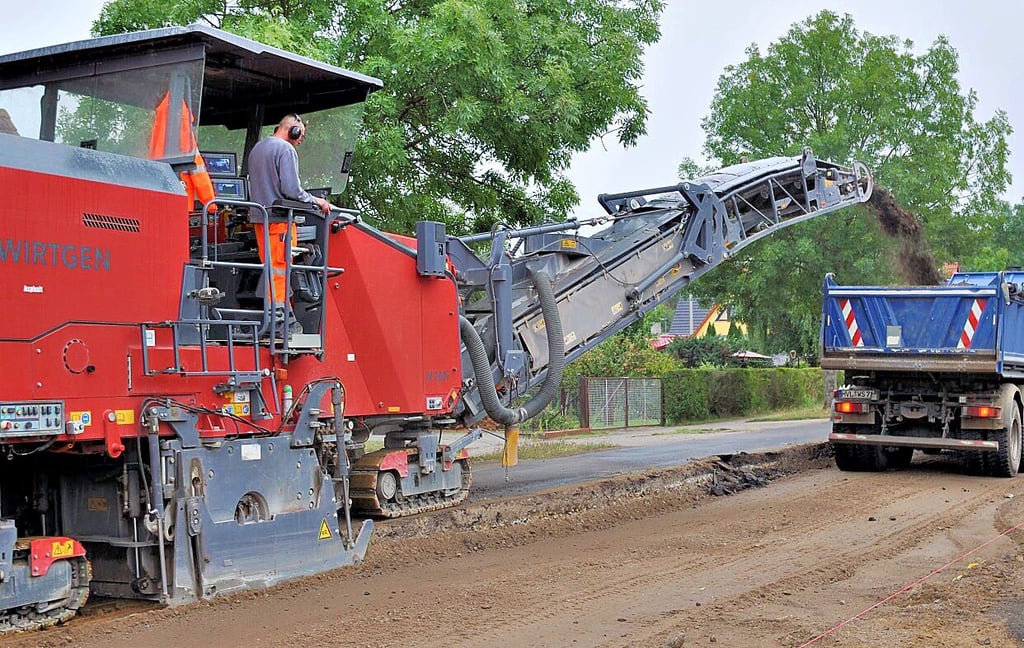 Innerhalb von zehn Minuten füllt die Fräsmaschine drei LKW-Hänger voll mit altem Straßenbelagschutt.